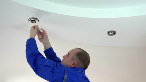 worker man install or replace halogen light lamp into ceiling