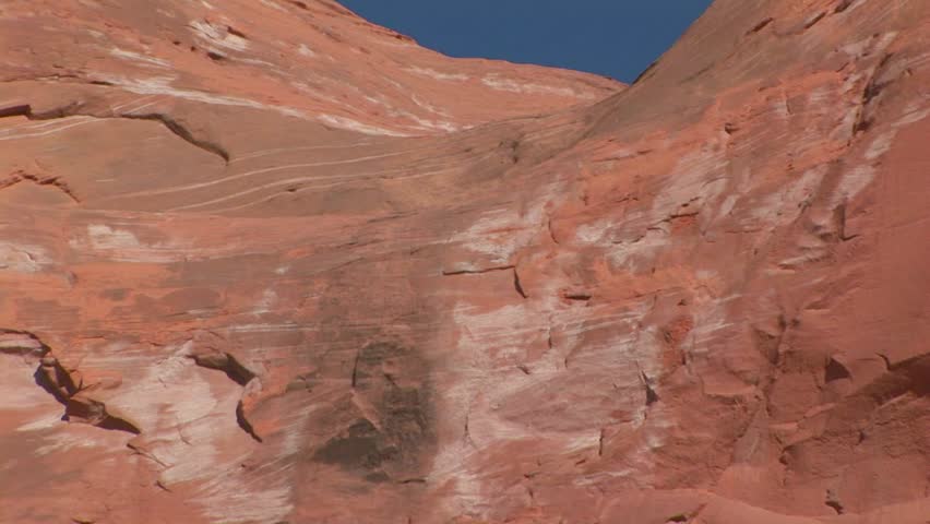 Back zoom from top of Wingate Cliff down to senior male standing at base of mountain at Red Rock Park in Gallup, New Mexico