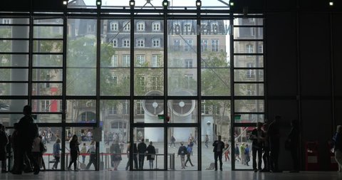 PARIS, FRANCE - SEPTEMBER 06, 2015: Low angle shot of many visitors walking around the big hall of Centre Georges Pompidou. Lobby with huge glass panes