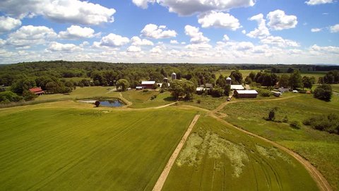 Working farm aerials, barn and buildings. Upstate New York. Puffy clouds. Float over differt views of a small farm.