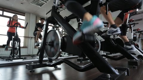Woman and man do on exercise bike in room with a glass wall.