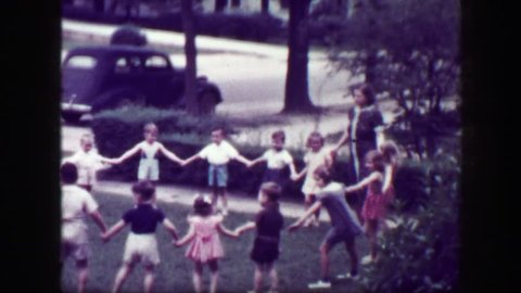 MACON, GEORGIA 1949: Schoolmarm teacher playing Hooky Pooky childhood game in house front yard.