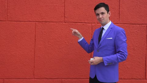  young magician in a suit shows a trick with cards on a red background