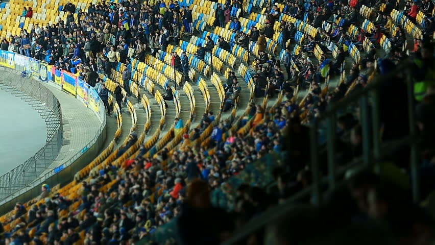 Football fans chanting, clapping hands on stadium tribunes, supporting teams