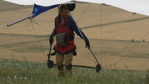 Guy pulls the hangglider into the mountain after a training flight from the top of the hill