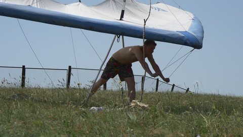 Guy holding the hang glider in the wind