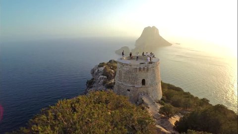 Aerial view of Torre del Pirata, an old tower on the top of a cliff, in front of the islet of Es Vedra, in the island of Ibiza, with a beautiful sunset.