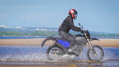 Extreme driving a motorcycle. A skilled biker riding on the edge of water