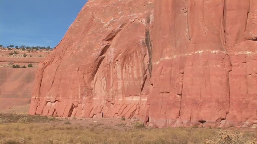Senior male walking alongside base of Wingate Cliffs at Red Rock Park in Gallup, New Mexico