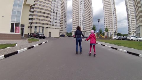 Boy, girl, woman roller skate near residential buildings