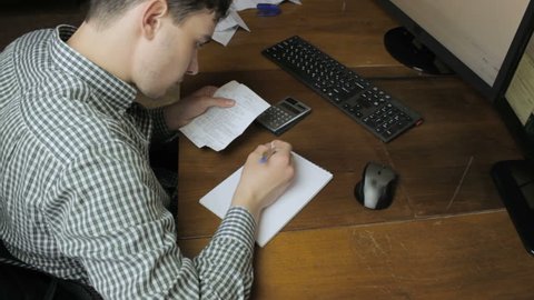 Man writes with payment checks to notebook