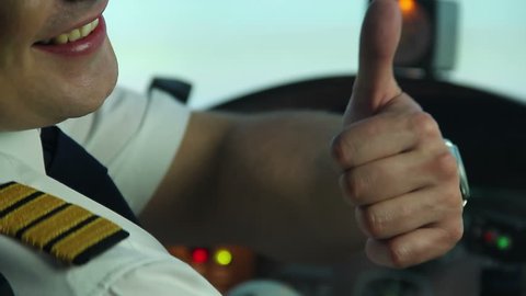 Happy professional pilot in cockpit showing thumbs up sign, enjoying his work. Professional airplane commander getting ready for taking off, nobel occupation, aviation. Happy aircraft crew member
