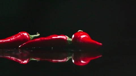 Four red Chili peppers falling down in slow motion on black background