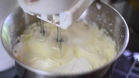 Mixing wipping cream with electric mixer close up