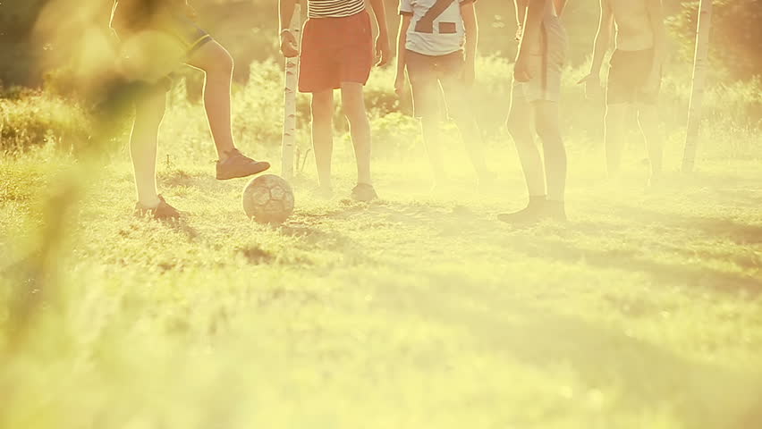 Local kids playing football in the village. Slow motion.