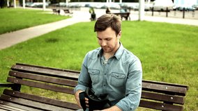 Young handsome man looking in virtual reality headset sitting on the bench outdoors