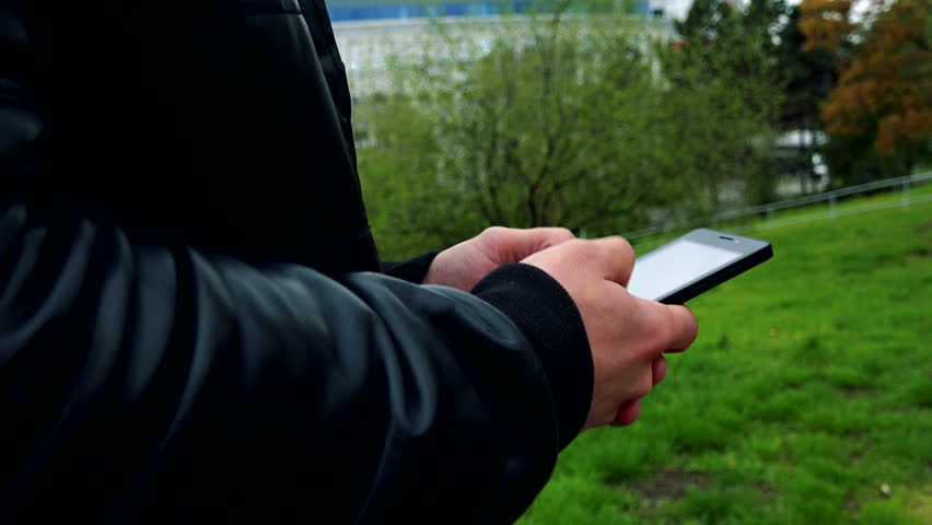 Young man goes and works on mobile phone - detail of hands