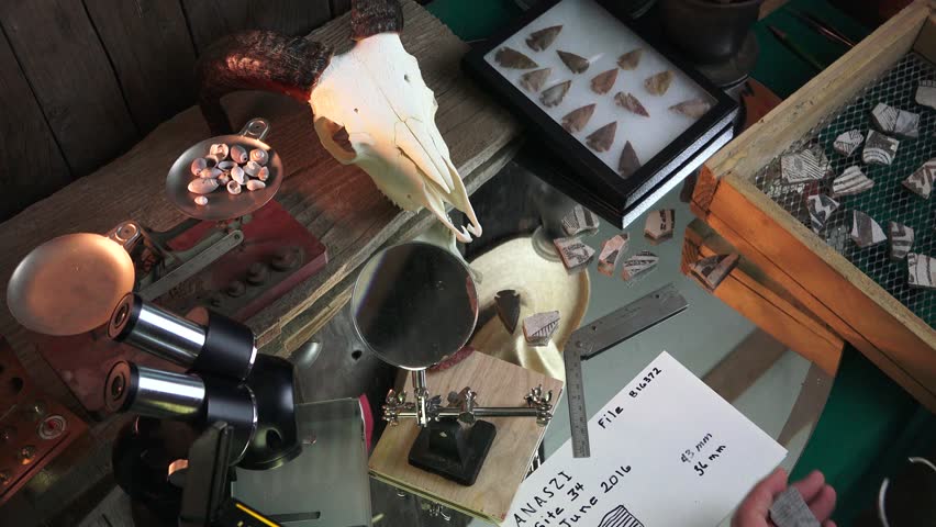 Archaeologist studying the recent finds from an Anasazi ruins in the Southwestern USA. Artistically painted shards of broken pottery and arrowheads are being studied and cataloged.