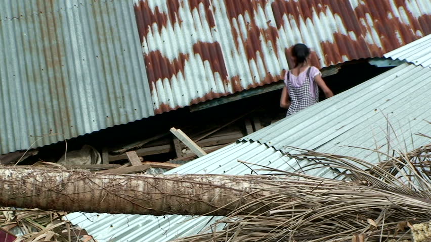 PADANG, INDONESIA - CIRCA OCTOBER 2009: A resident stands outside remains of