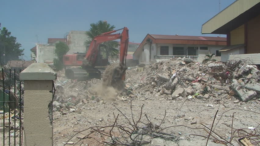 PADANG, INDONESIA - CIRCA OCTOBER 2009: Excavator clears rubble in aftermath of