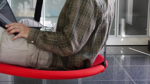 a man works with his notebook and a mobile in a swinging seat