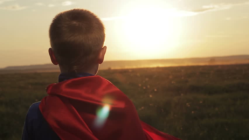 Boy dressed with a Superman cape running in a field, looking into the sunset. Superhero kid flying on sunset sky background. Power concept. Child pretending to be superhero. Royalty-Free Stock Footage #17661979