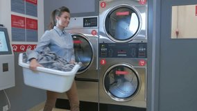 Beautiful woman doing laundry at laundromat shop in 4k UHD video.