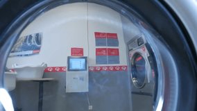 Handsome man doing laundry at laundromat shop in 4k UHD video.
