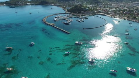 Scenic top view of a beautiful marina in the Caribbean. Panning aerial view of beautiful sailboats on the Saint Martin harbor in Marigot. Aerial video of a beautiful sunrise in the Caribbean sea.