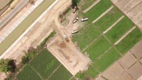 Aerial shot of excavator machine loads a dump truck on harvest field in 4k video