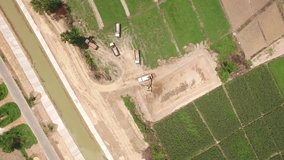 Aerial shot of excavator machine loads a dump truck on harvest field in 4k video