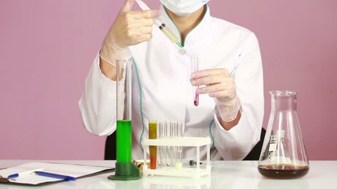 Female chemist comparing test tubes with chemicals. protective glasses