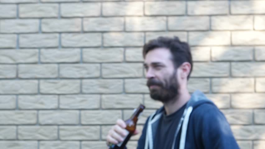 man in front of brick wall standing drinking looking like in group