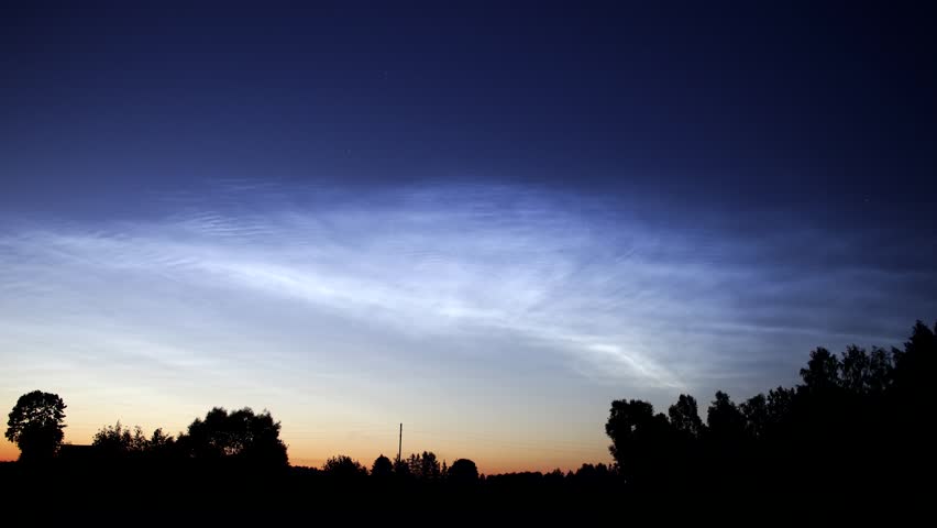 A rare sky phenomenon - noctilucent clouds over ladscape, time-lapse .