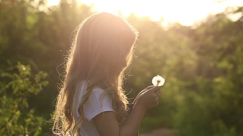 Little cute girl blow a dandelion. Rest at nature. Slow motion
