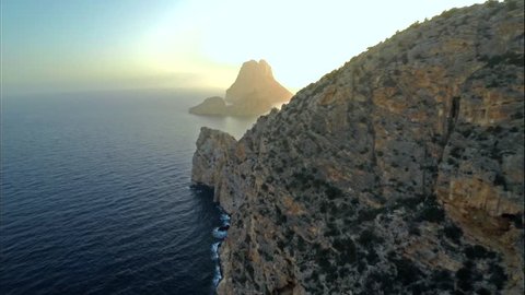 Aerial view of a cliff, in front of an islet named Es Vedra, at sunset, in the island of Ibiza.
