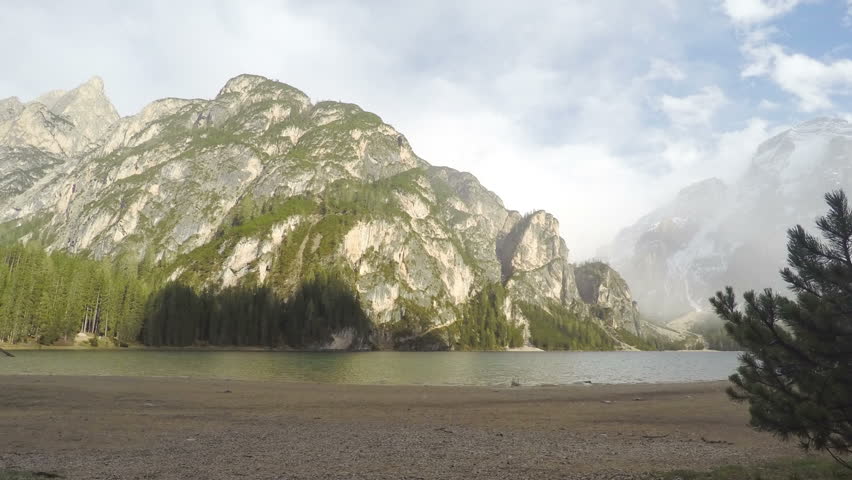 Timelapse of clouds above mountains and lake Pragser Wildsee in Italy, tourism