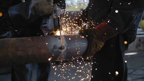 Worker Cutting Steel Pipe with Angle Grinder