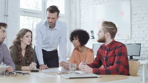 Manager talking with coworkers at creative agency office during business meeting