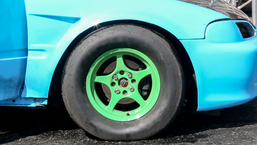 Drag racing car burns rubber off its tire in preparation for the race