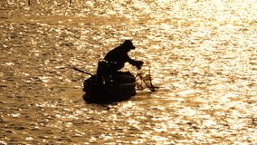 4K video silhouette fishermen working on little colorful boat in golden lake at sunrise time,select focus.