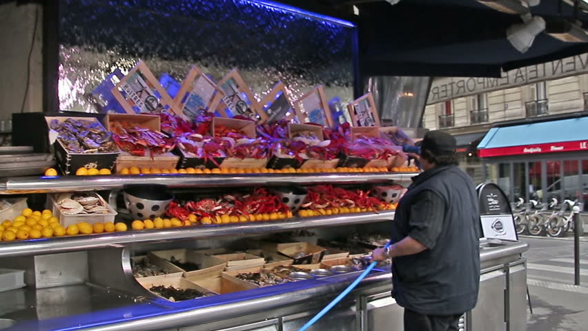 PARIS, FRANCE - March 22, 2016: Seller pouring water from a hose on seafood