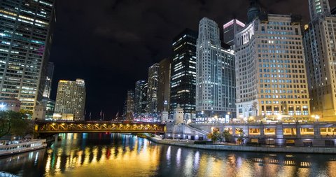 Chicago, Illinois, USA - view from the bottom of Trump Tower of DuSable Bridge with Chicago River facing east along the Riverwalk with skyscrapers at night - Timelapse with zoom out - October 2014