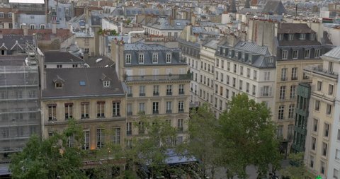 View to Paris with classic architecture and flying pigeons. Birds settling on one of the house roofs