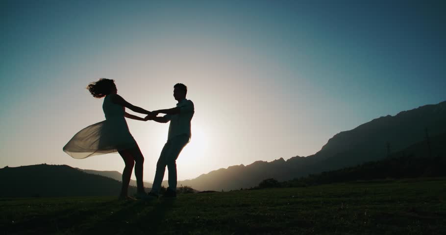 Romantic young couple silhouette. woman and man holding hand in circle together,dawn, the glare of the sun, love story, slow motion