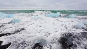 Blocks of ice washed by the waves on Jokulsarlon beach. White nights in Iceland, Europe. Full HD video (High Definition).