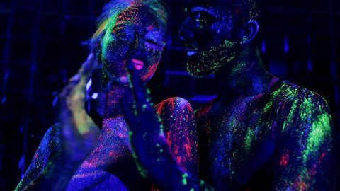 Tender touch of loving couple in ultraviolet light. People are colored fluorescent powder. Unreal love in ultraviolet light. Love and passion in ultraviolet light.