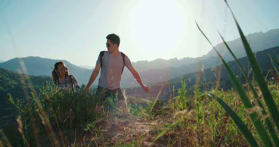 Couple climbing mountain range, hand reaches out to help,slow motion