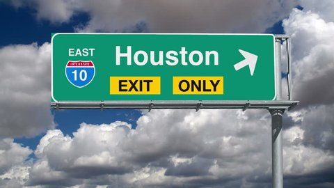 Houston Interstate 10 exit sign with time lapse clouds.