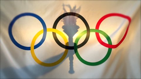 RIO DE JANEIRO - FEBRUARY 26, 2016: Silhouette of hand holding sport torch behind the rings of an Olympic flag  in anticipation of the city hosting the Summer Games.